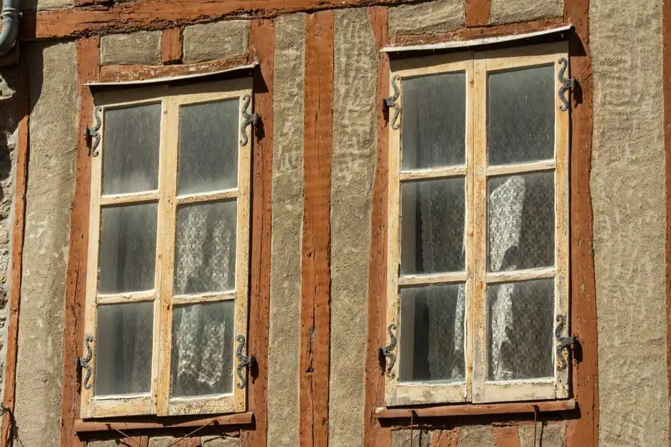 Close-up of rustic vintage windows with wooden frames on a traditional facade.