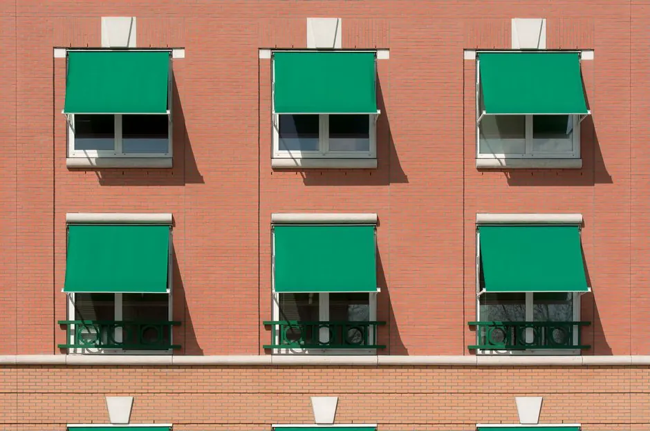 Exterior view of a brick apartment building with green awnings.