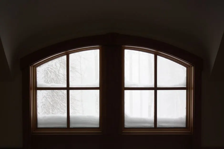 Interior view of an arched window covered with snow, creating a cozy winter atmosphere.