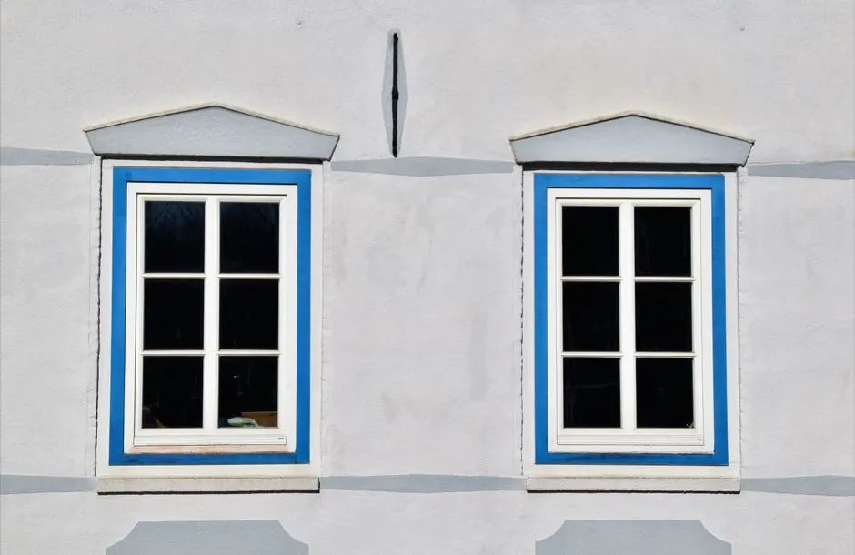 Two decorative windows with blue trim on a building in Glückstadt, Germany.